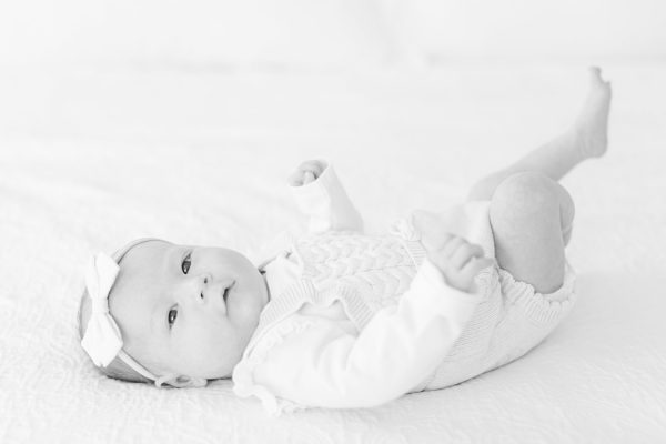 Baby girl laying on back in bed in Westfield NJ.
