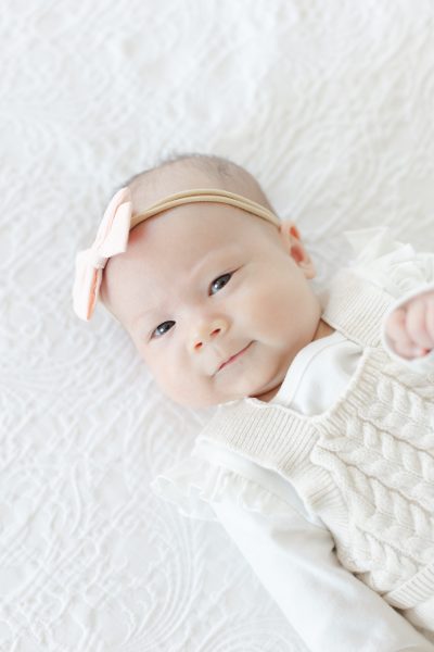 A baby girl wearing a pink bow smiling in Westfield NJ.