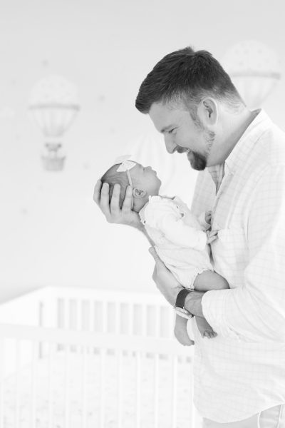 A dad and holds his baby and smiles at her in Westfield NJ.