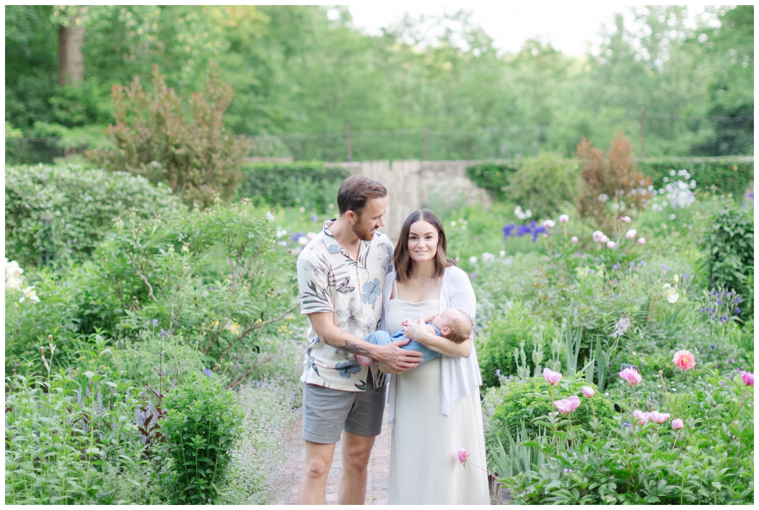 Mom and dad with their newborn son in garden at Cross Estate Gardens.