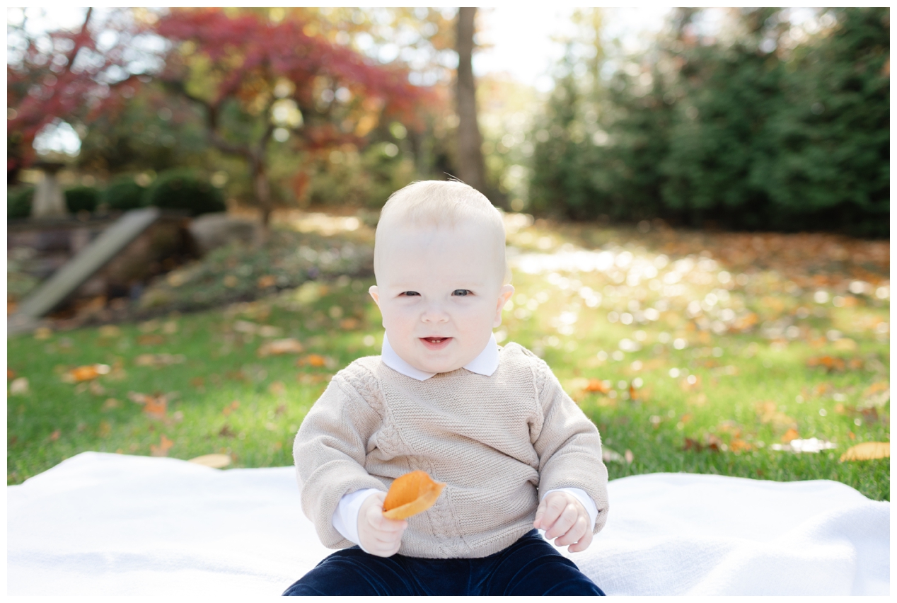 Baby boy smiling holding a leaf during family portaits in Summit NJ.